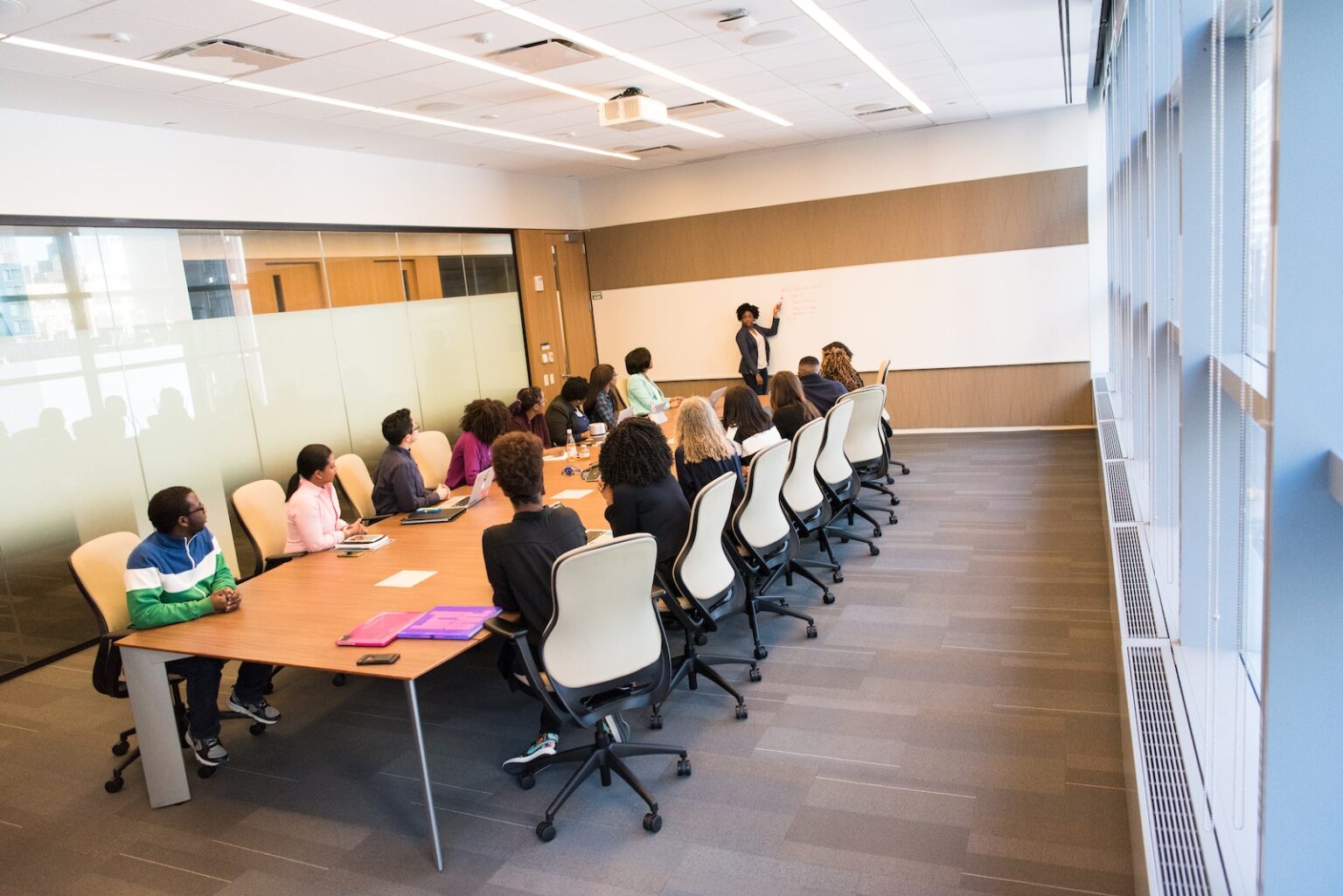 People Sitting on Beige Rolling Chairs on Brown Wooden Table Inside Room